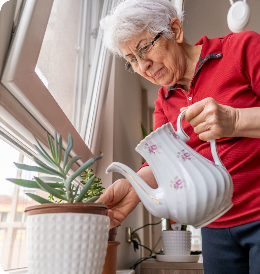 Ältere Dame gießt Blumen